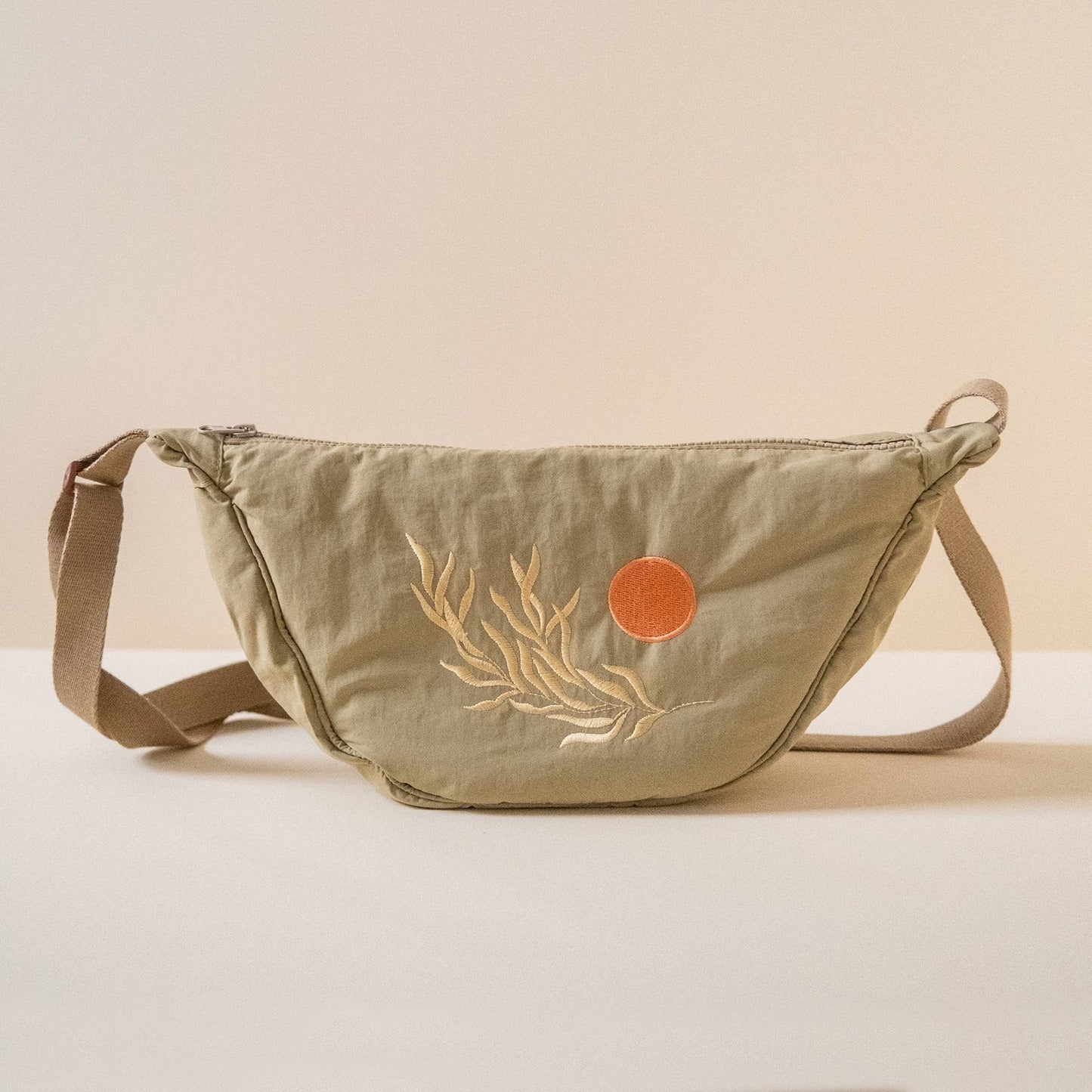 Green sling bag with beige leaf design and orange circle embroidered
