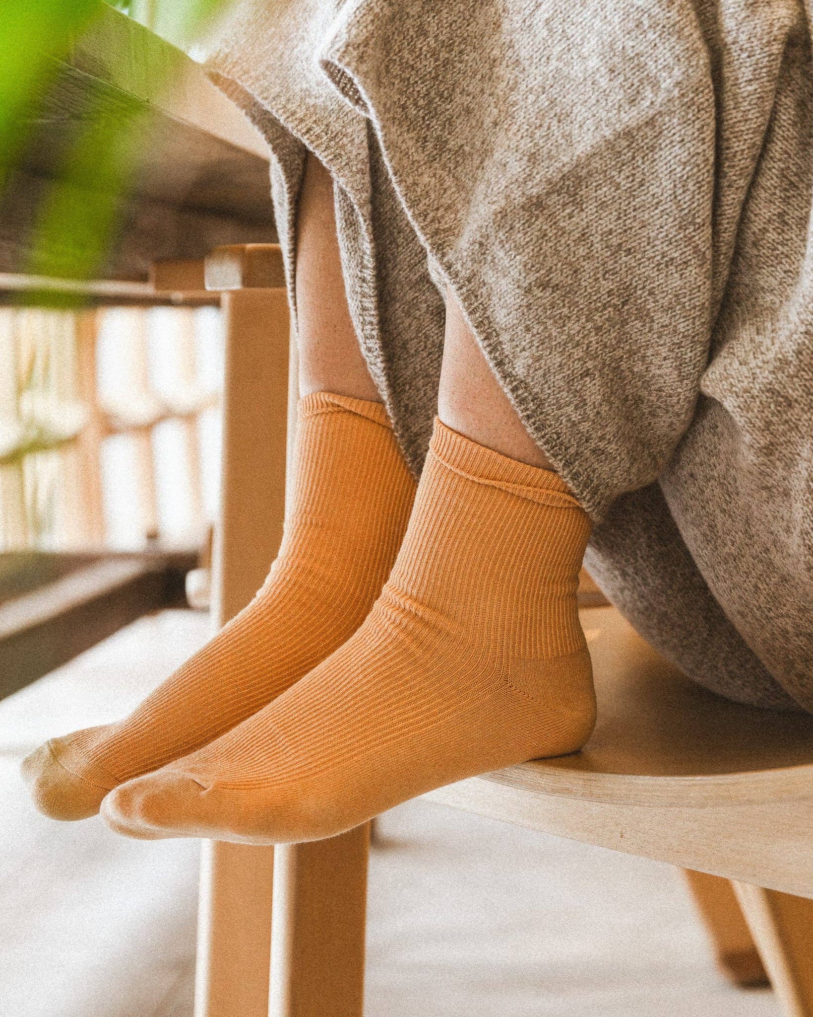 A woman sitting on a chair with her feet in the seat wearing yellow socks