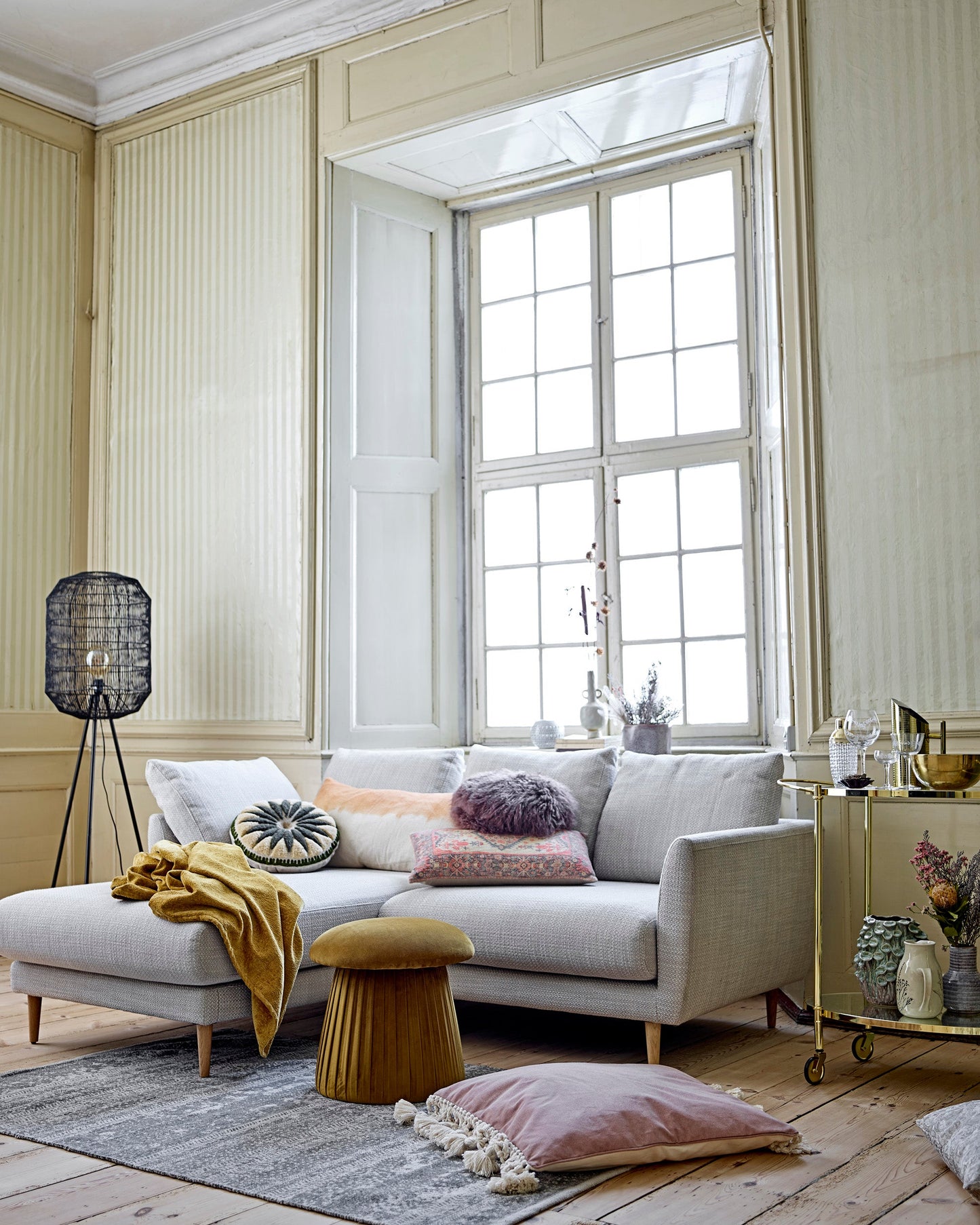 Modern living room with a gray sofa, decorative pillows, and a large window.