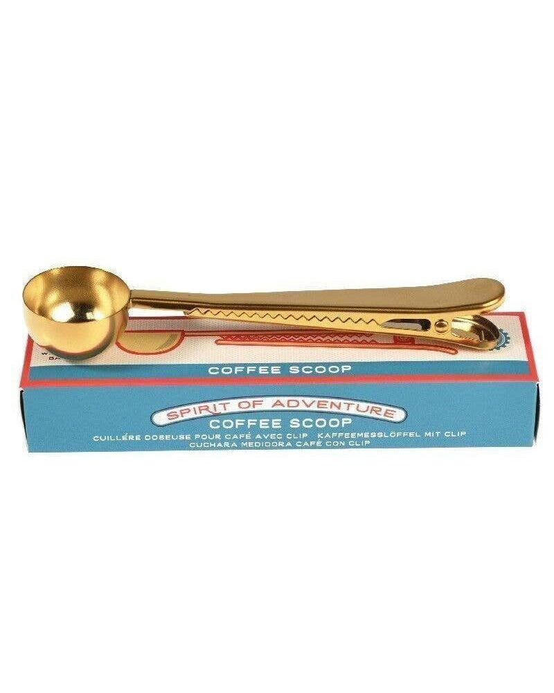 Gold coffee scoop with packaging on a white background