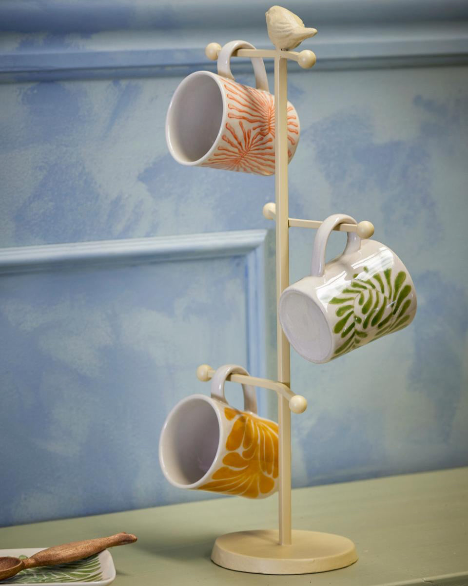 Mug rack with three ceramic mugs on a light blue background