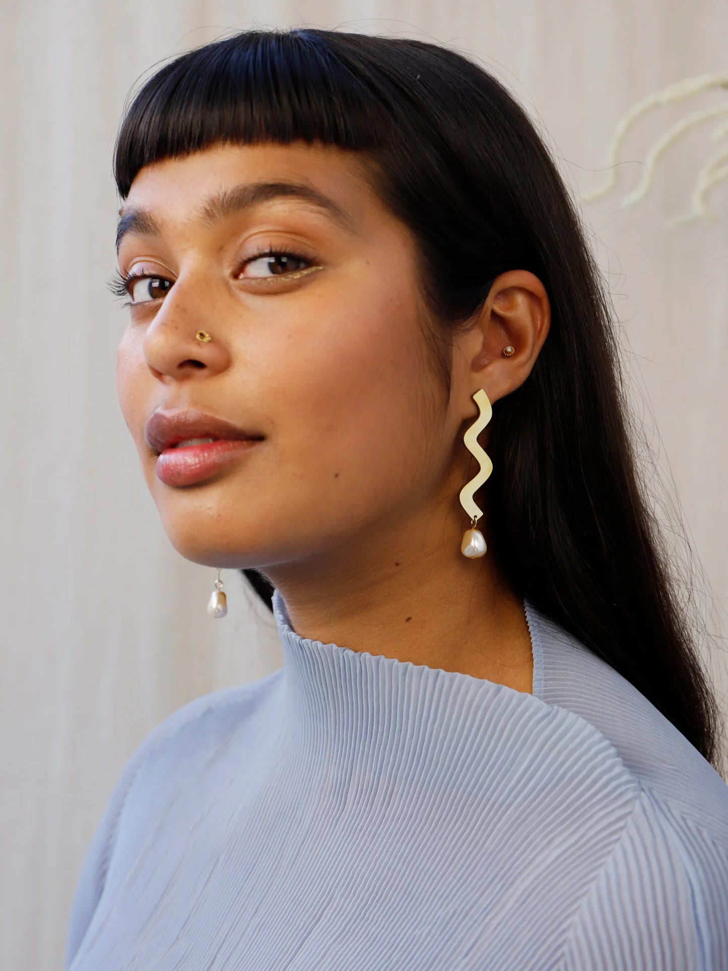 Wavy asymmetric statement earrings made in brass with Wolf & Moon's signature wood base, Czech glass baroque pearls, 14k gold-filled chain and sterling silver earring posts, on model