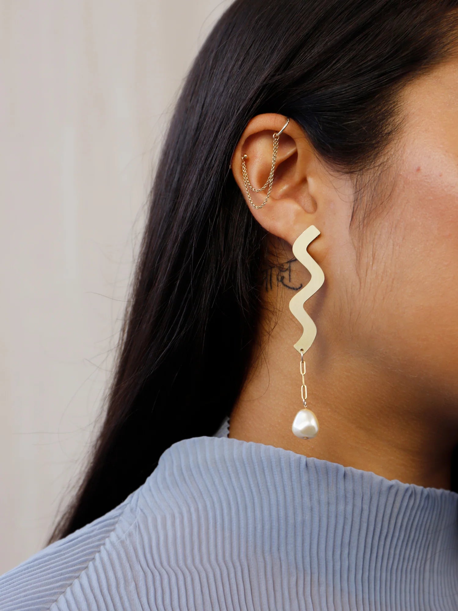 Close up of Wavy asymmetric statement earrings made in brass by Wolf & Moon