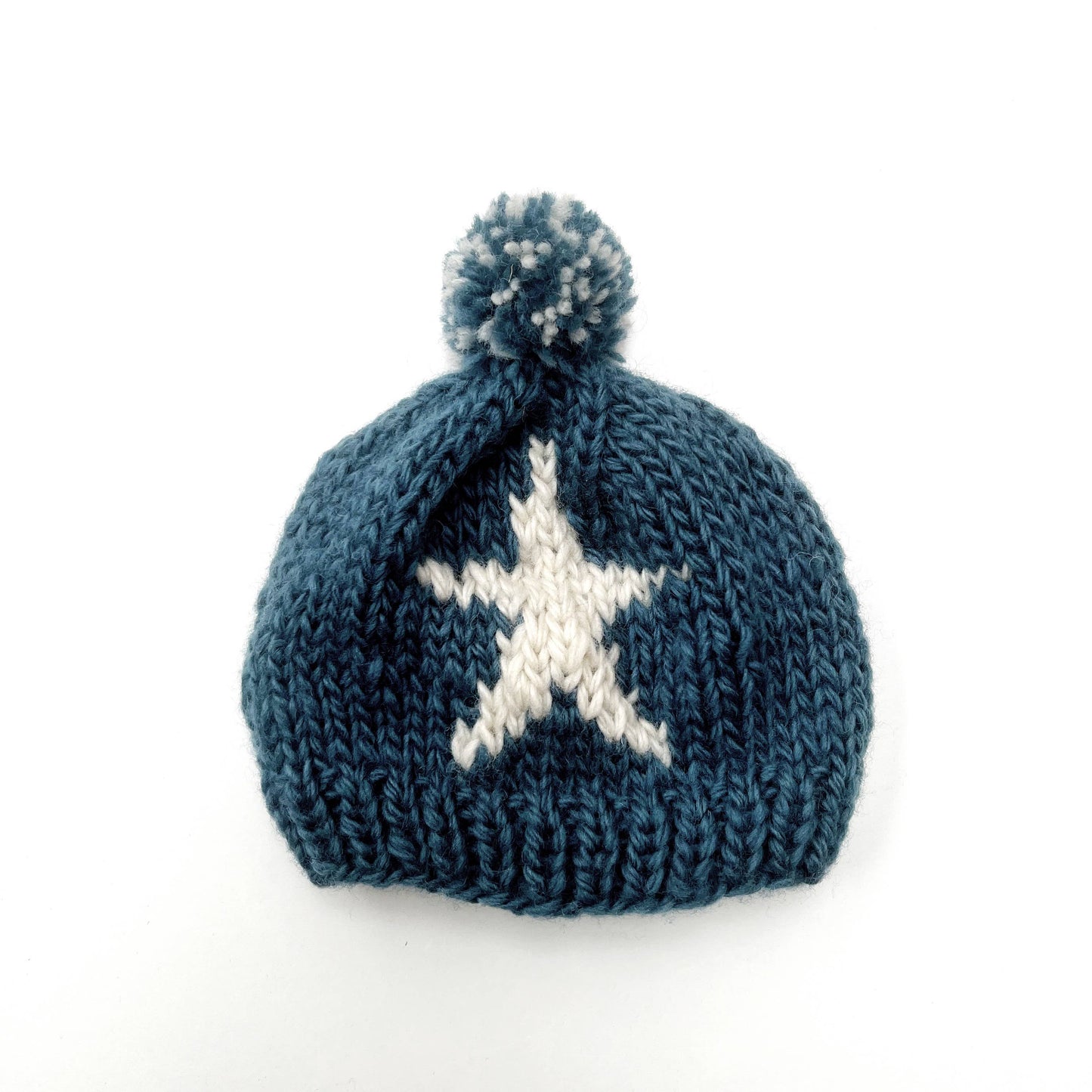 Thick, chunky woollen baby winter hat, by Pebble Child, made from 100% New Zealand merino wool in teal colour with a white star and a pompom on top.
