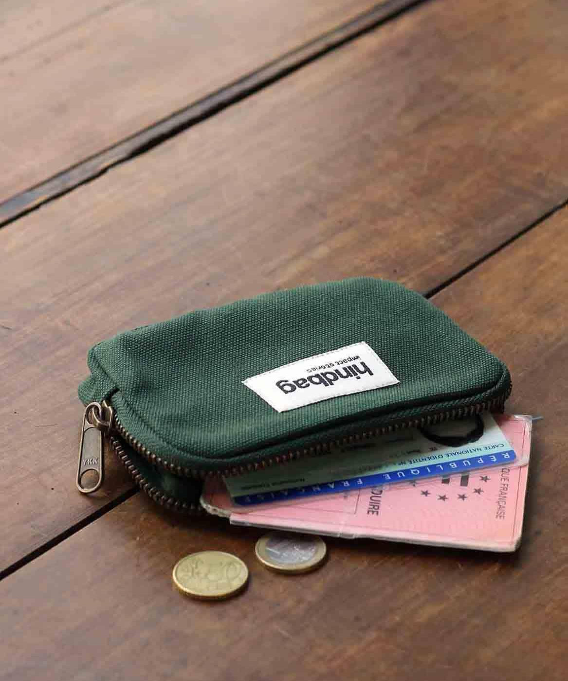 Green wallet with a brand label on a wooden surface