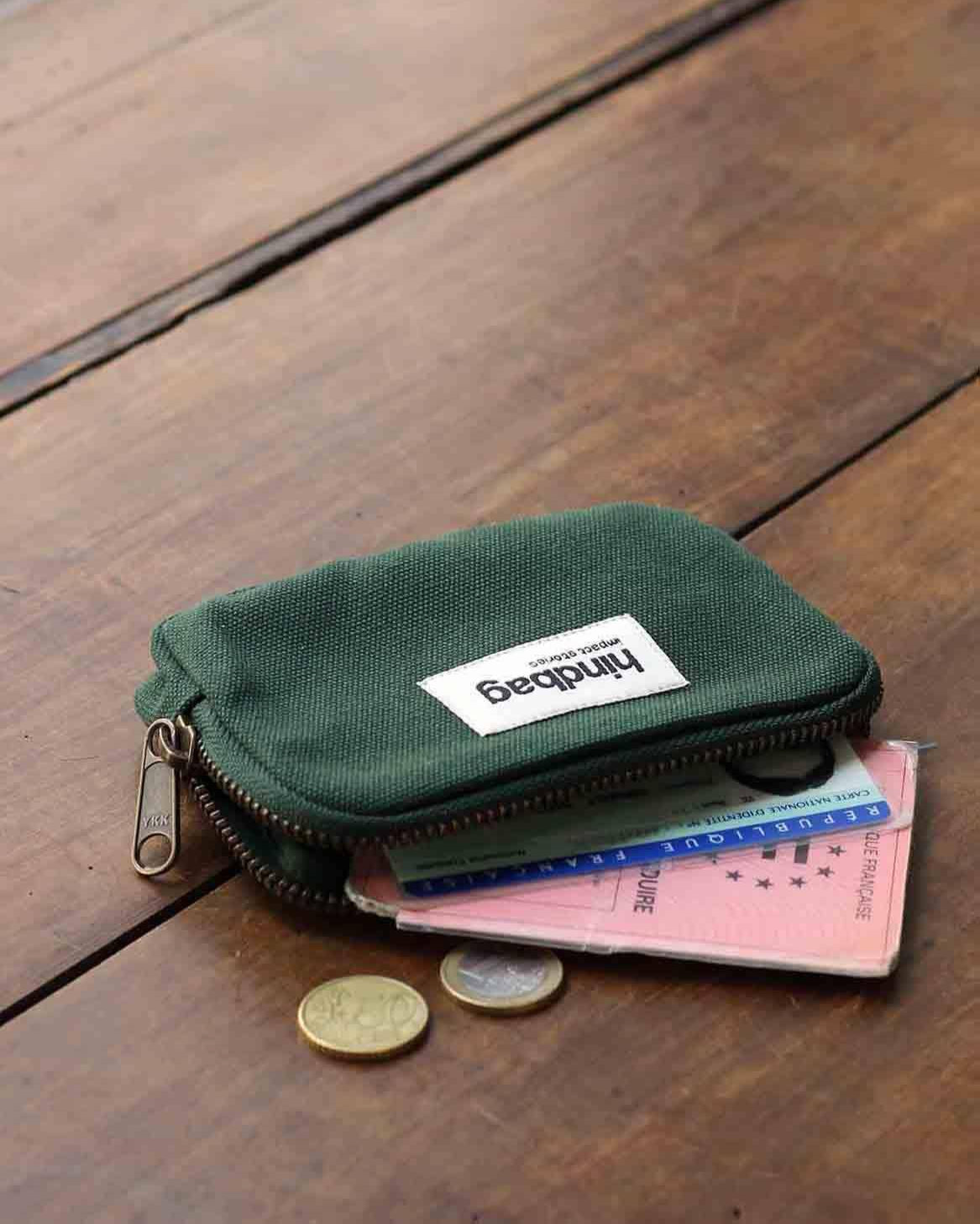 Green wallet with a brand label on a wooden surface