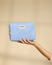 Hand holding a blue pouch with 'hindbag' label against a beige background