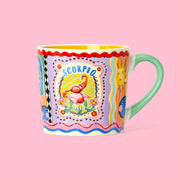 A multicolored mug with a Scorpio zodiac sign design, featuring pastel colors and gold foil detail.
