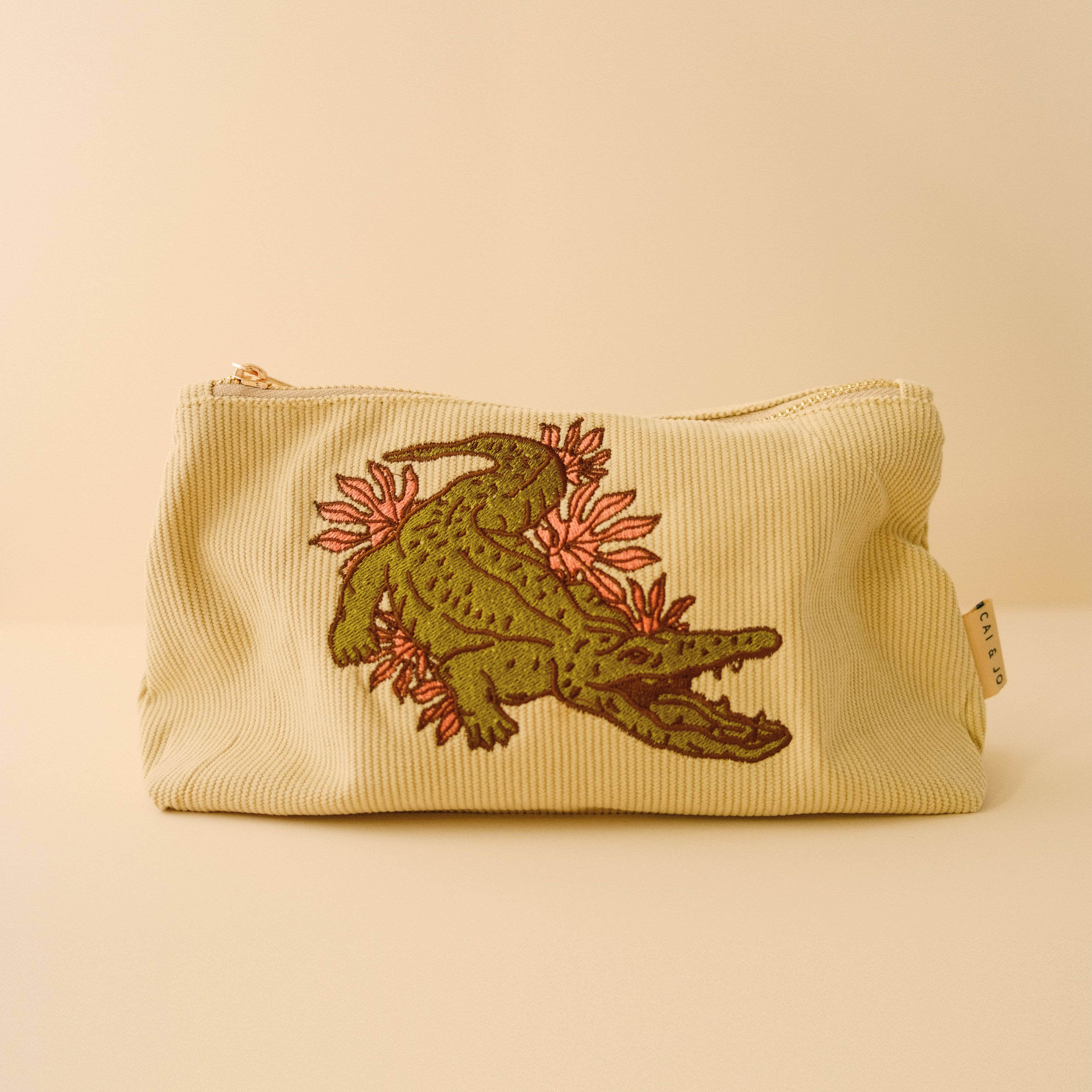 Sage green corduroy pouch with green crocodile and pink foliage embroidered on the pouch
