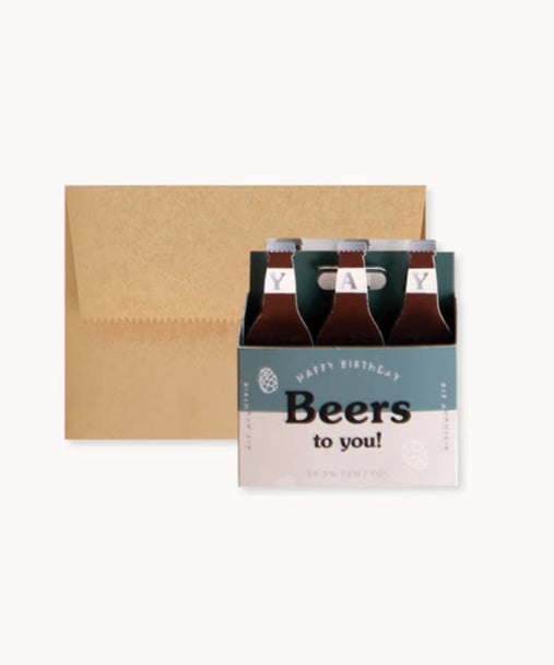 Six-pack of beer with a 'Happy Birthday Beers to you!' card on a white background