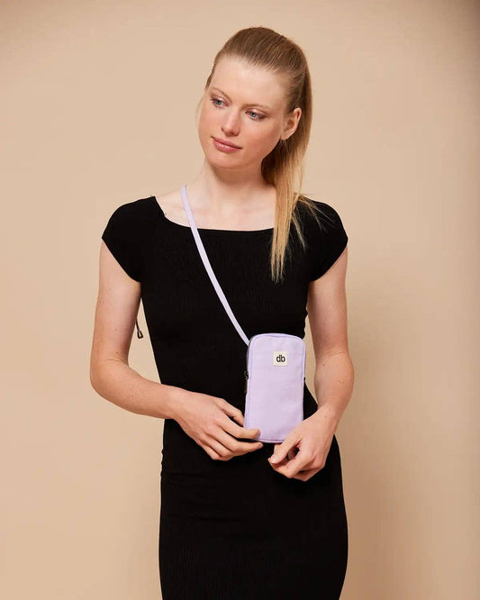 Woman holding a lilac crossbody phone bag, with zip section for phone and back pocket for bank cards