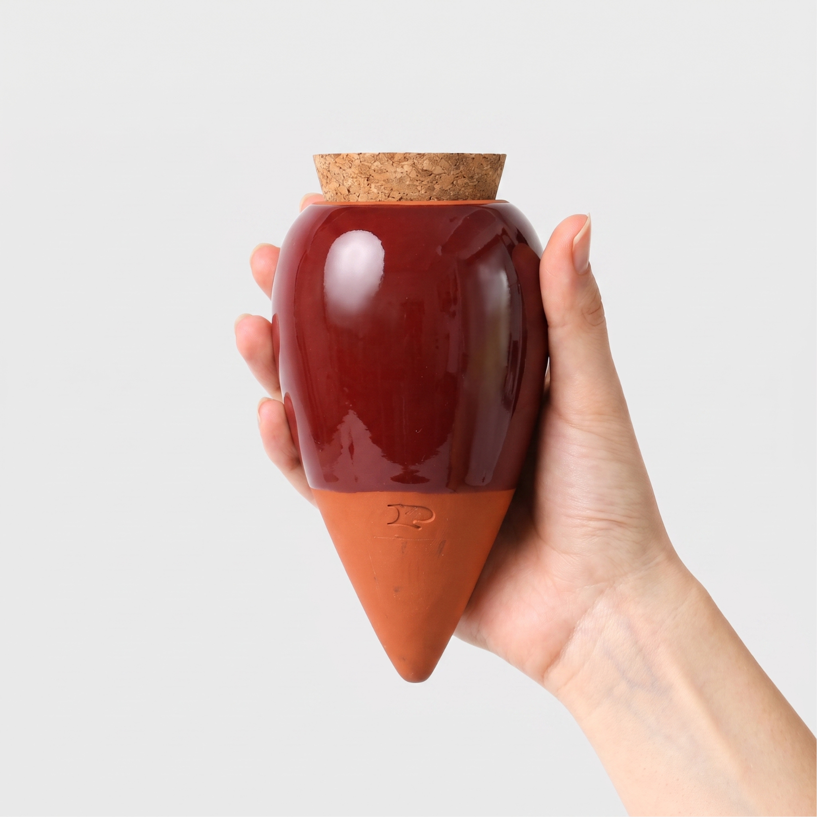 Pepin olla plant waterer in burgundy glazed terracotta, held in a hand