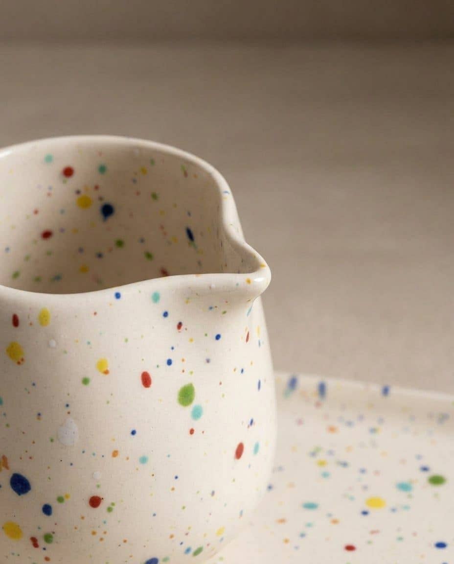 Egg Back Home white ceramic jug with multicoloured speckles on a beige background