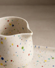 Egg Back Home white ceramic jug with multicoloured speckles on a beige background