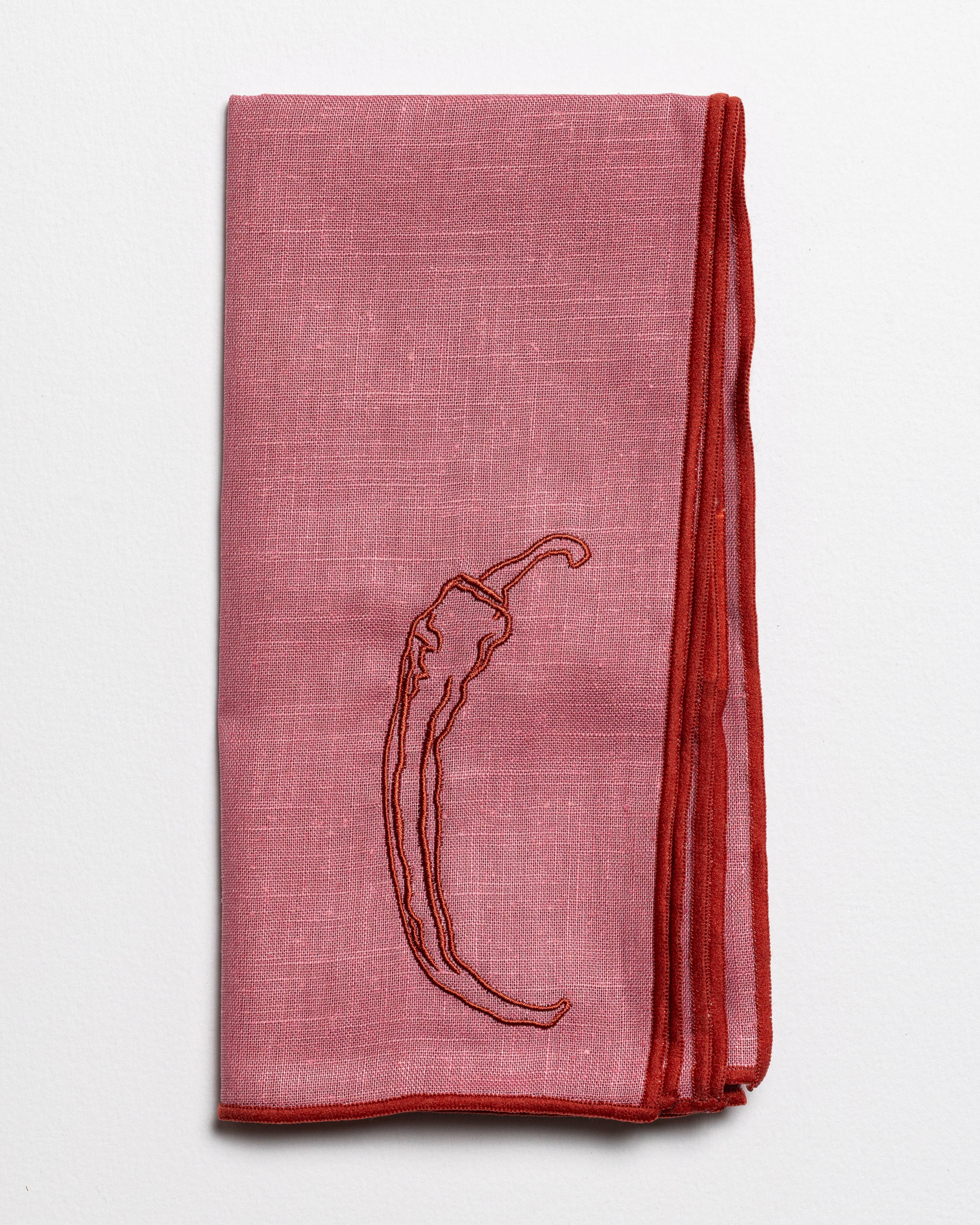 Close up of the embroidered chilli design on a linen napkin