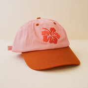 Pink and burnt orange cap with an embroidered hibiscus design 