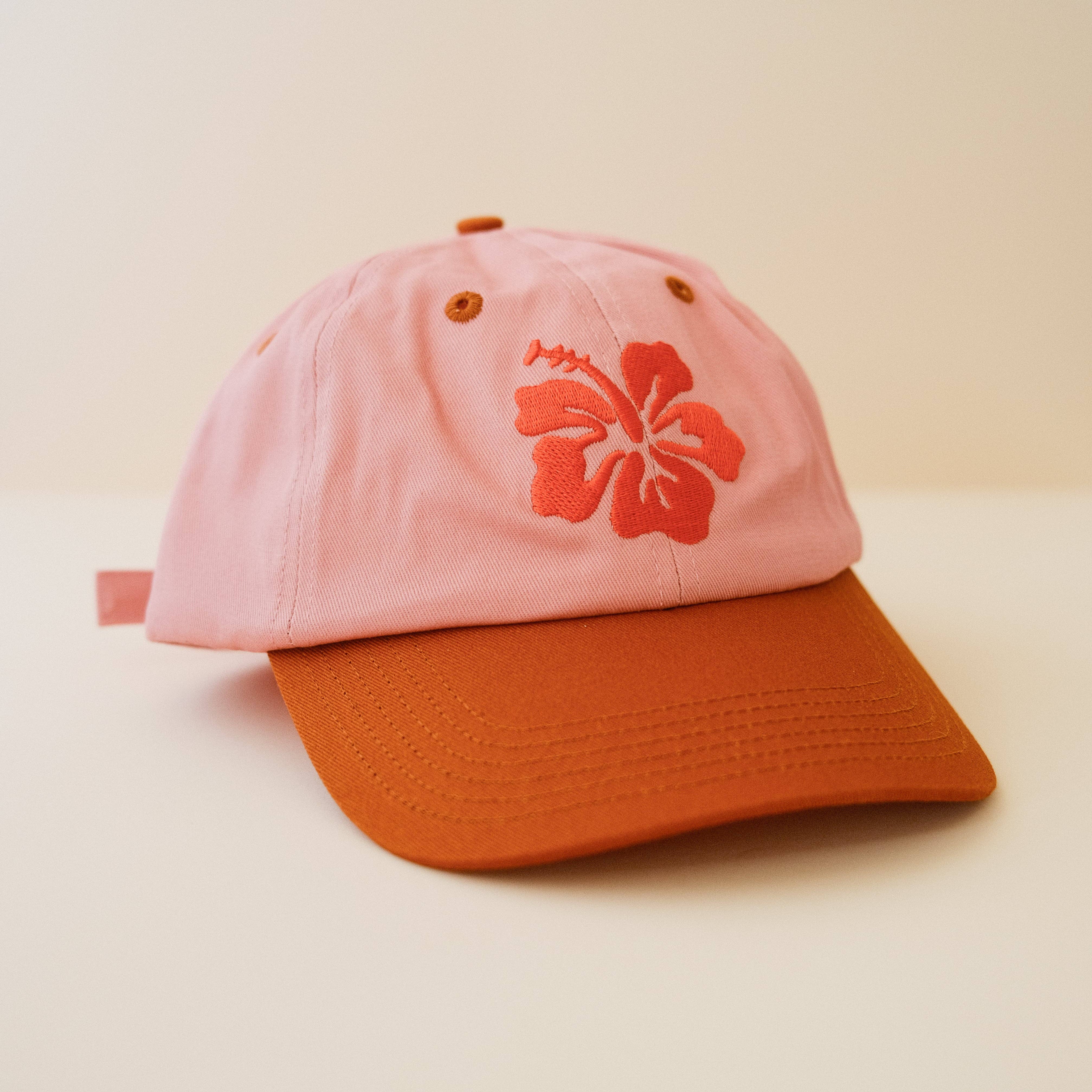 Pink and burnt orange cap with an embroidered hibiscus design 