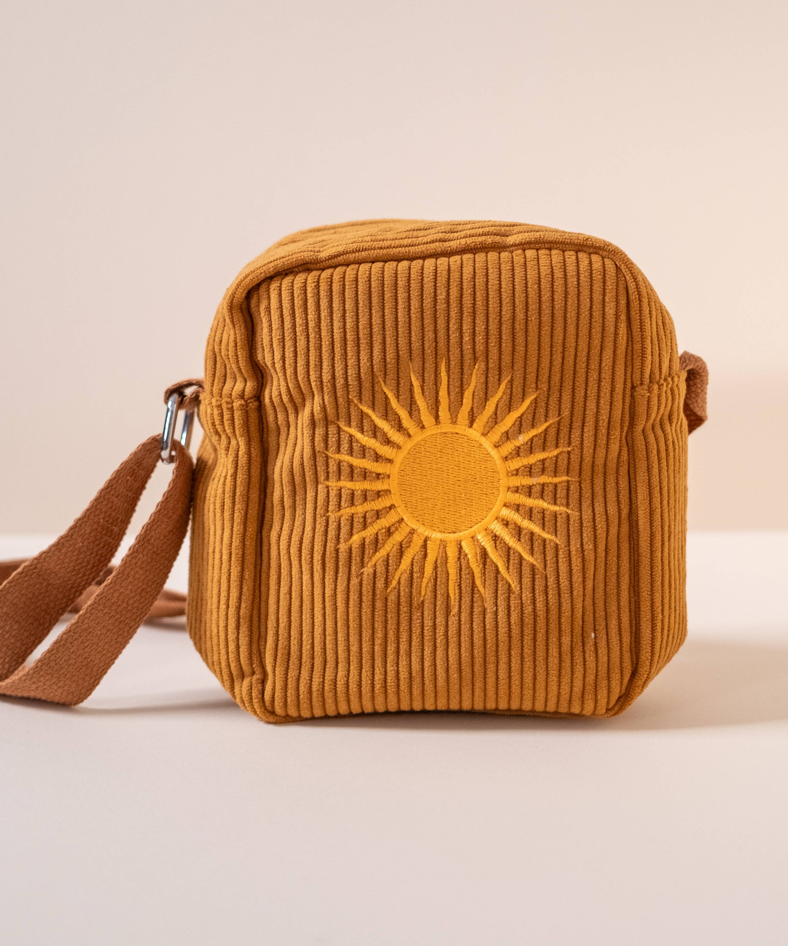 Brown corduroy bag with sun design on a beige background