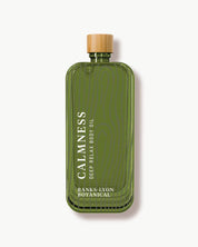 Green bottle of 'Calmness' body oil with a wooden cap on a white background