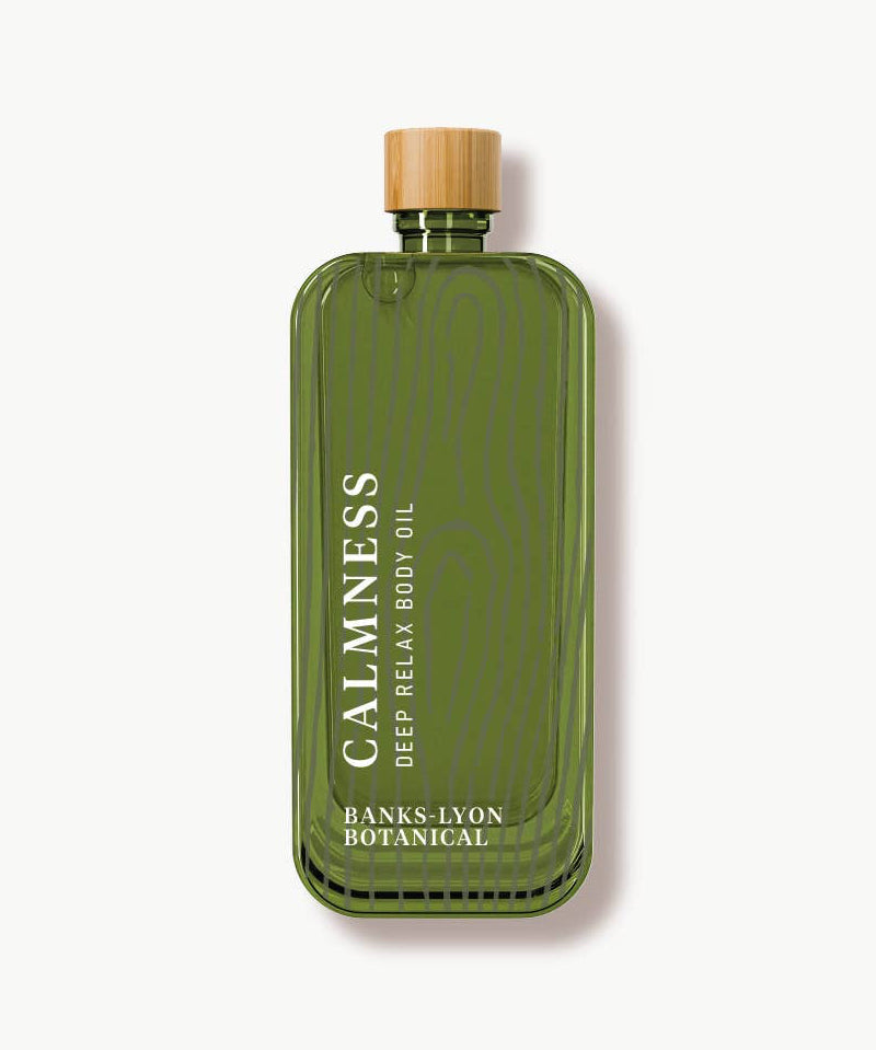 Green bottle of 'Calmness' body oil with a wooden cap on a white background