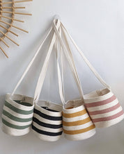 Set of four striped bags hanging on a hook against a white wall.