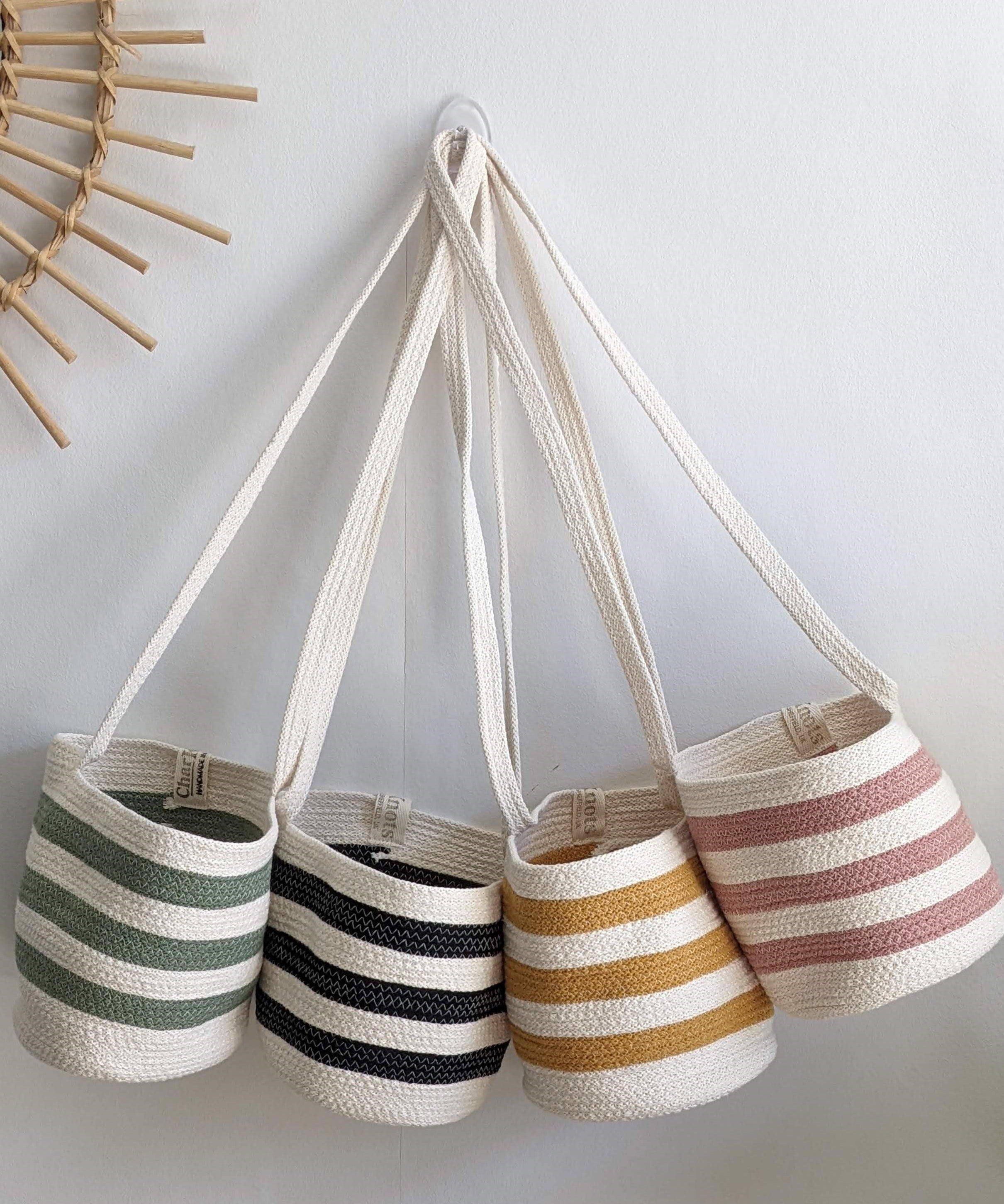 Set of four striped bags hanging on a hook against a white wall.