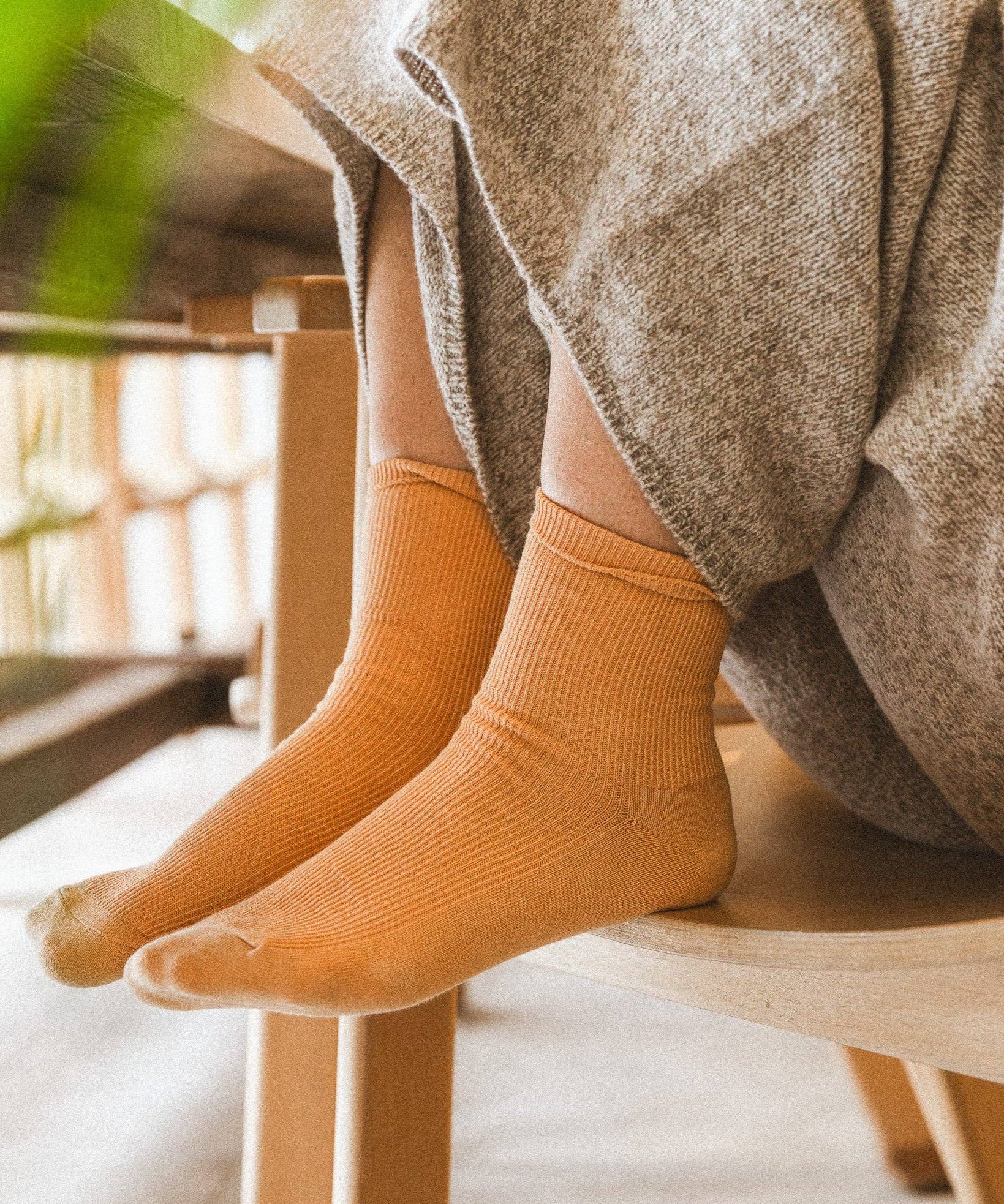 A woman sitting on a chair with her feet in the seat wearing yellow socks