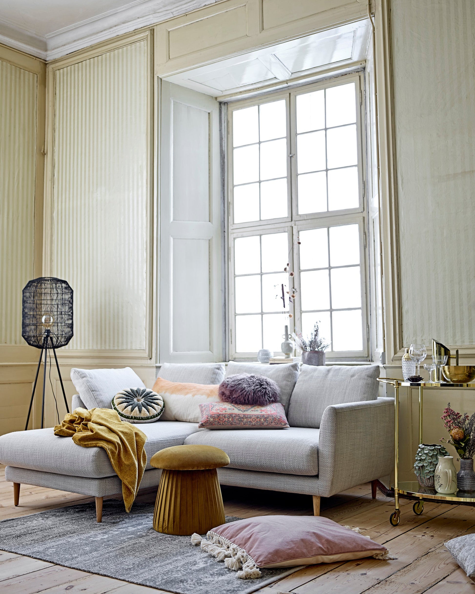 Modern living room with a gray sofa, decorative pillows, and a large window.