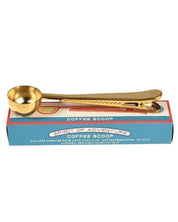 Gold coffee scoop with packaging on a white background