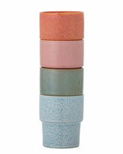 Stack of three ceramic cups with different colored finishes on a white background