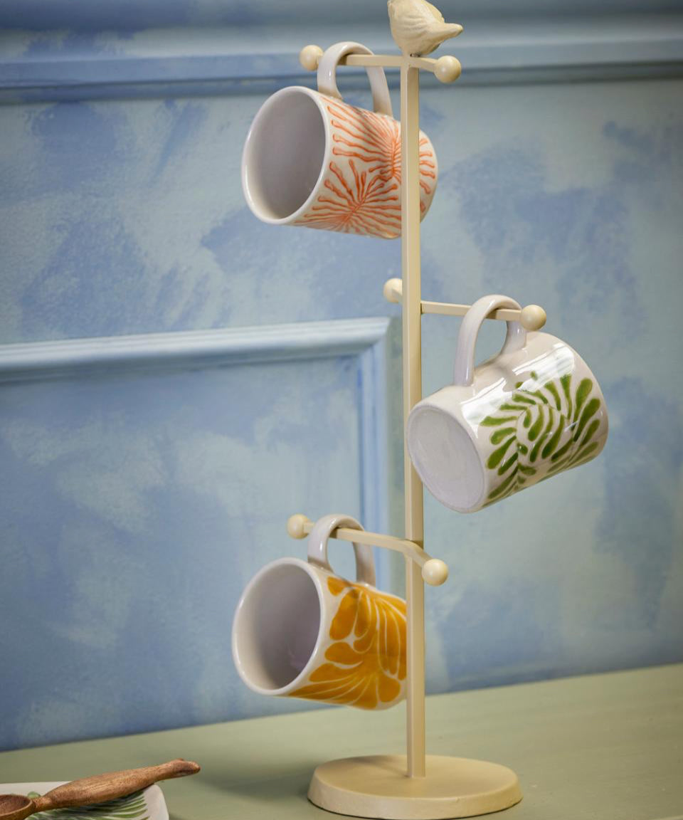 Mug rack with three ceramic mugs on a light blue background