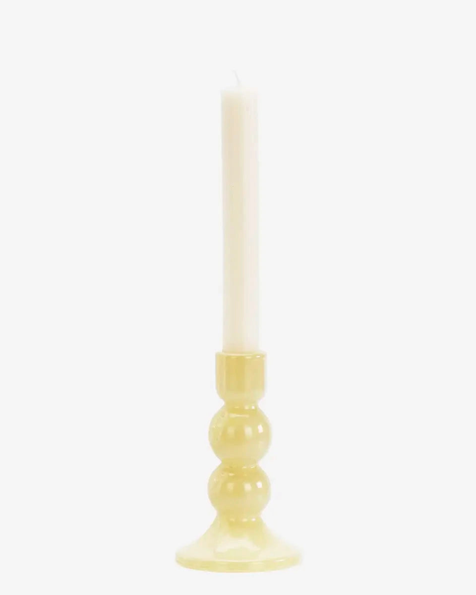 Candle in a yellow holder on a white background