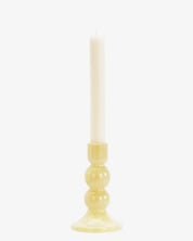 Candle in a yellow holder on a white background