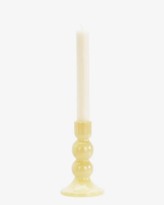 Candle in a yellow holder on a white background