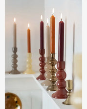 Colorful candles in various holders on a white surface