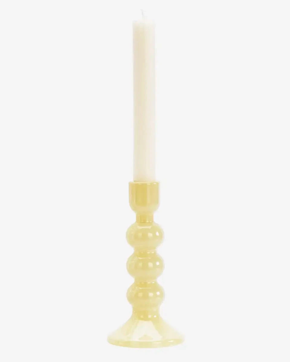 Yellow candle holder with a white candle on a white background