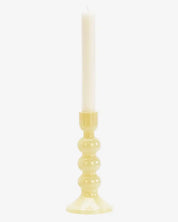 Yellow candle holder with a white candle on a white background