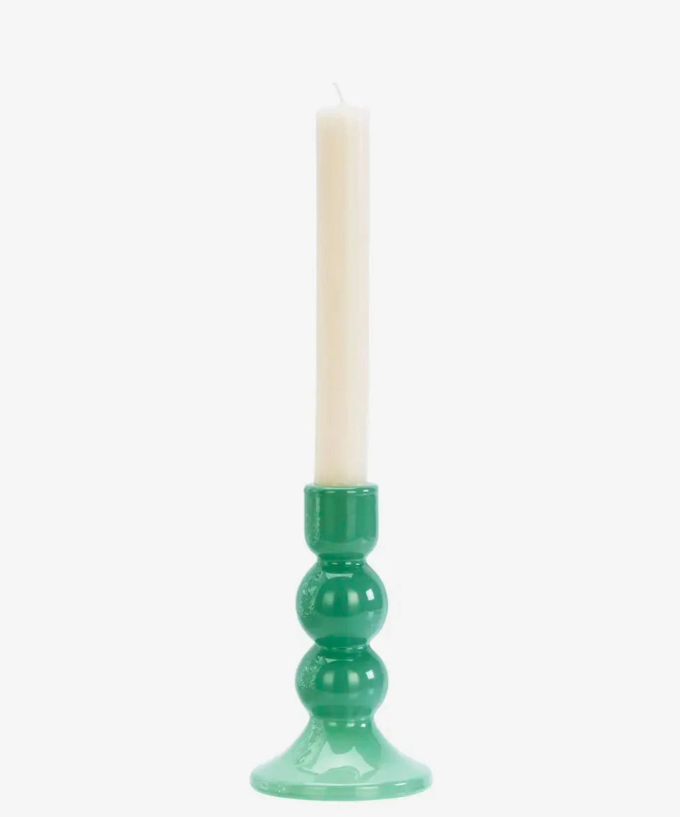 Green candle holder with a white candle on a white background