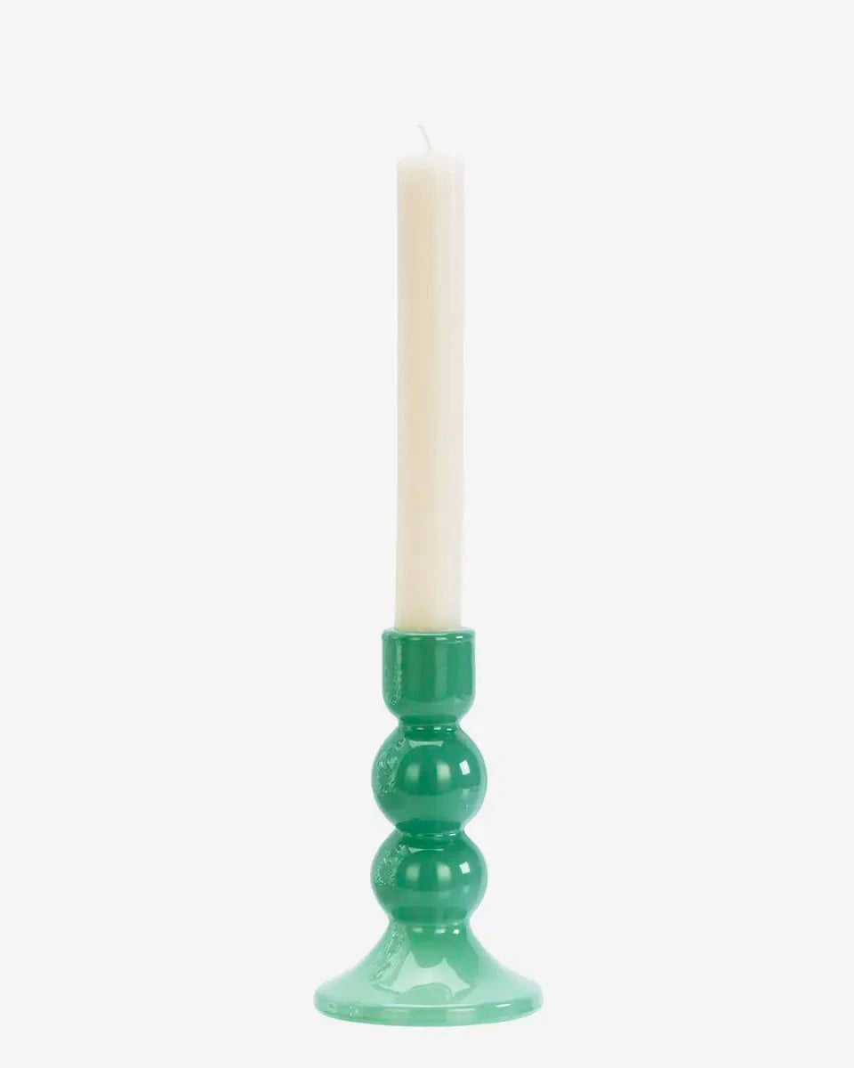 Green candle holder with a white candle on a white background
