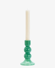 Green candle holder with a white candle on a white background