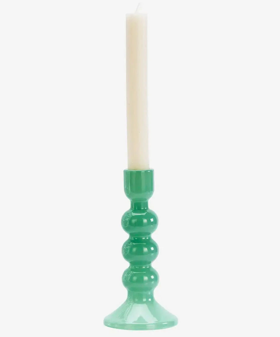 Green candle holder with a white candle on a white background