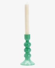 Green candle holder with a white candle on a white background