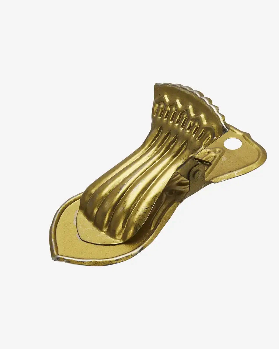 Gold bottle opener with decorative design on a white background