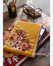 Yellow embroidered blanket with floral patterns on a wooden surface