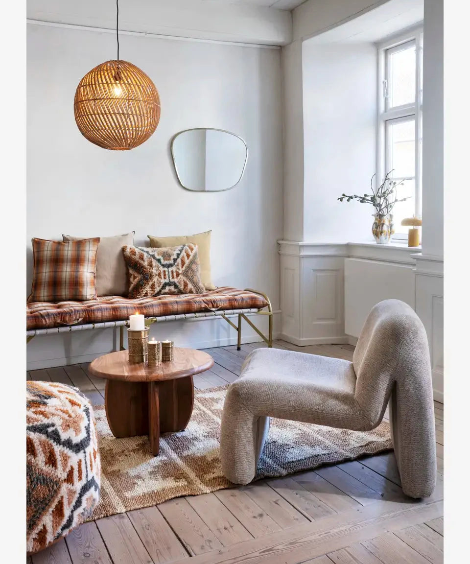 Modern living room with a unique chair, round table, and plaid cushions.