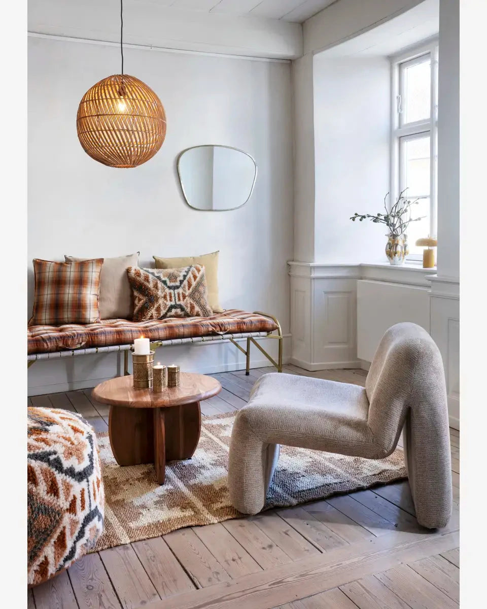 Modern living room with a unique chair, round table, and plaid cushions.