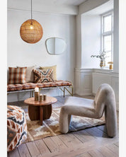 Modern living room with a unique chair, round table, and plaid cushions.