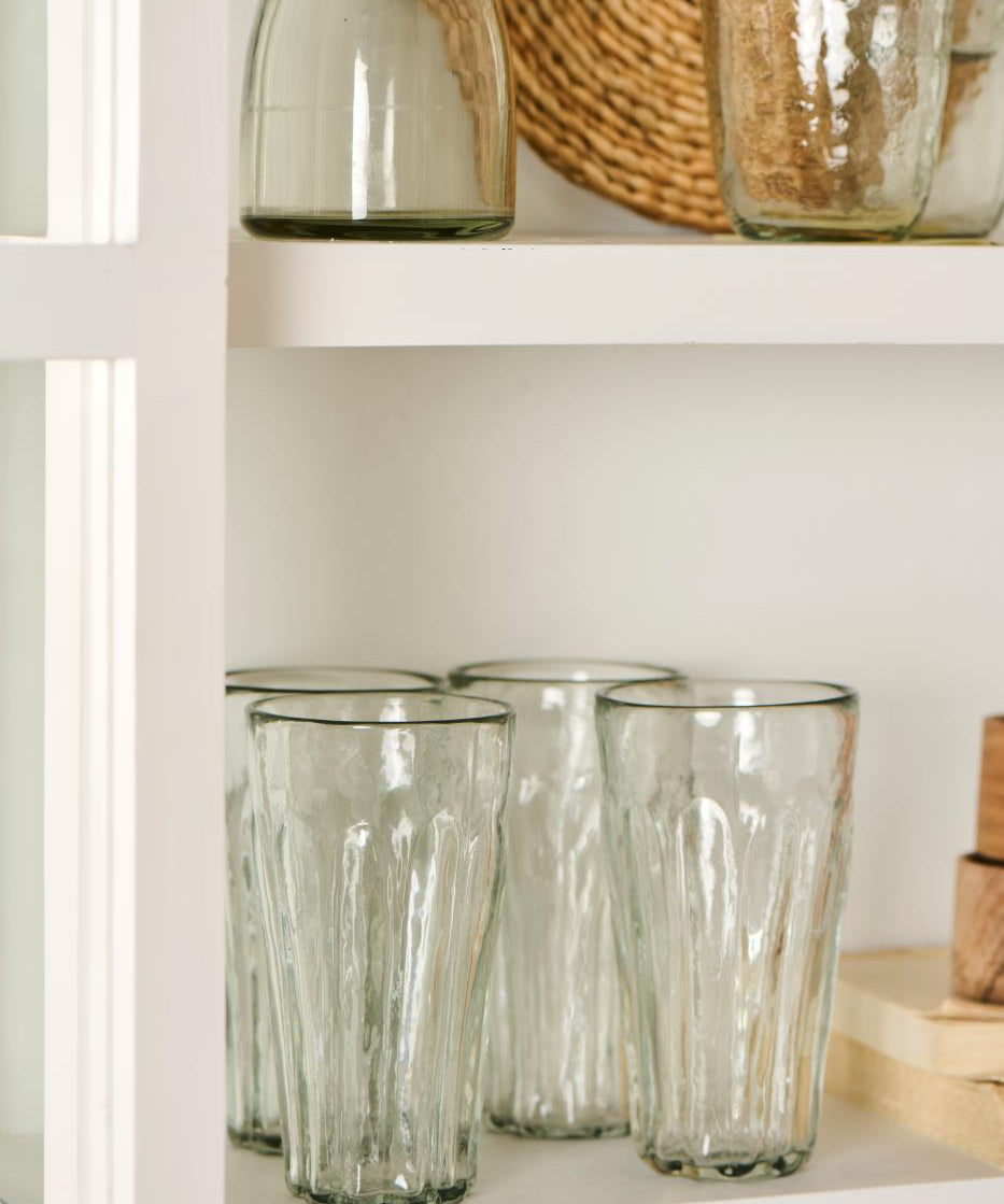 Clear glass tumblers on a white shelf with a woven basket in the background
