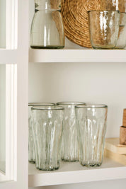 Clear glass tumblers on a white shelf with a woven basket in the background