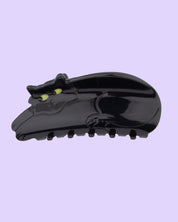 Black cat hair law with yellow eyes on a light purple background